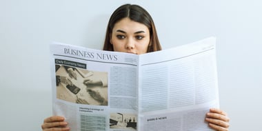 woman holding up newspaper to read