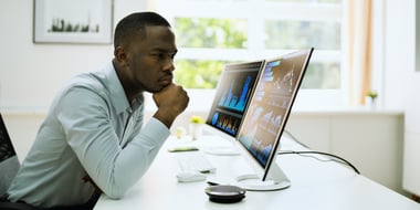 man working at desk staring at computer screen of analytics